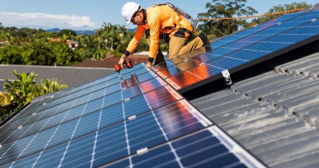 Homme qui installe des panneaux solaires sur un toit 