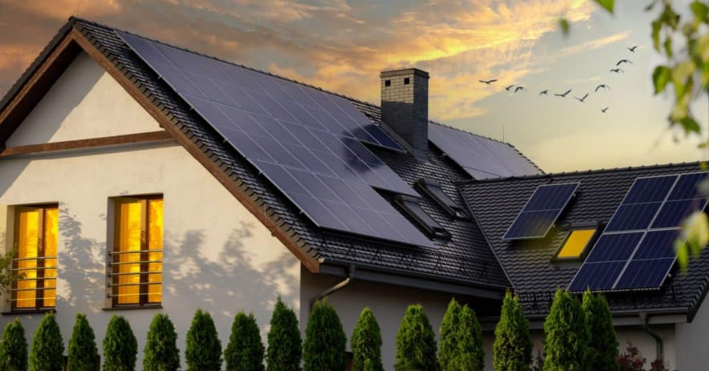 Une maison au toit incliné avec des panneaux solaires et une cheminée