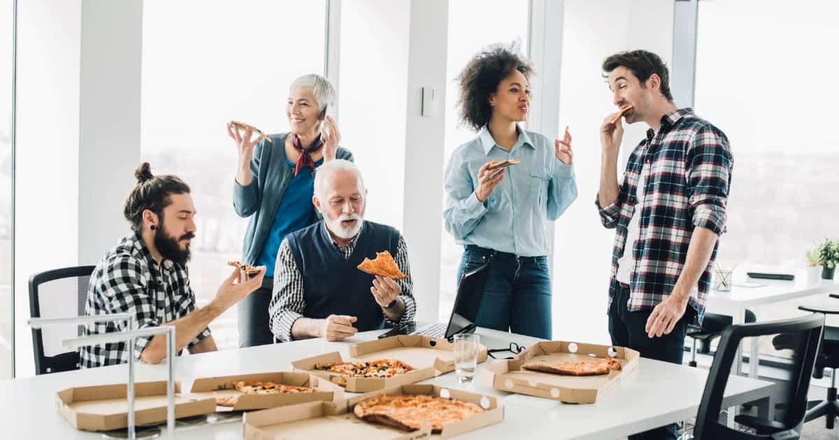 Groupe de collègues partageant des pizzas au bureau.