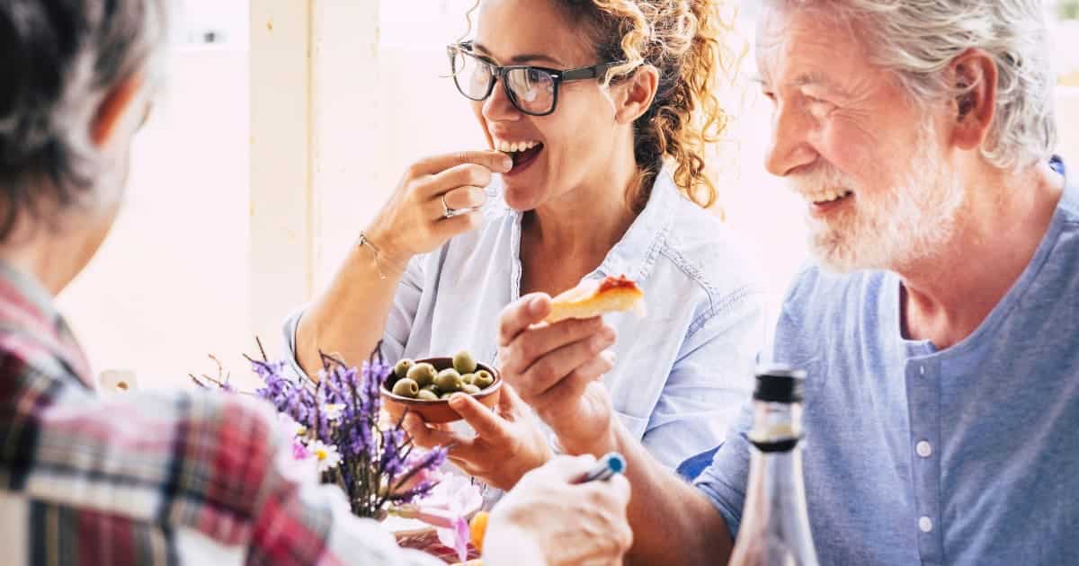 Personnes partageant un repas convivial avec des olives et du pain.