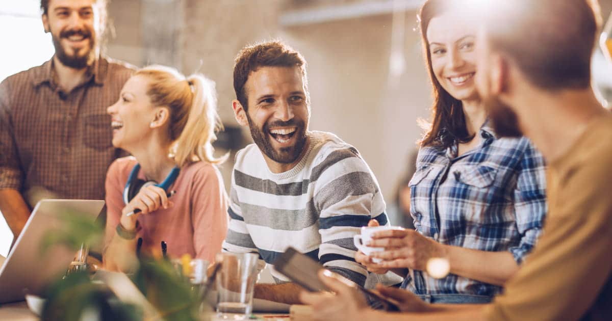 Collègues souriants partageant un moment convivial au travail.