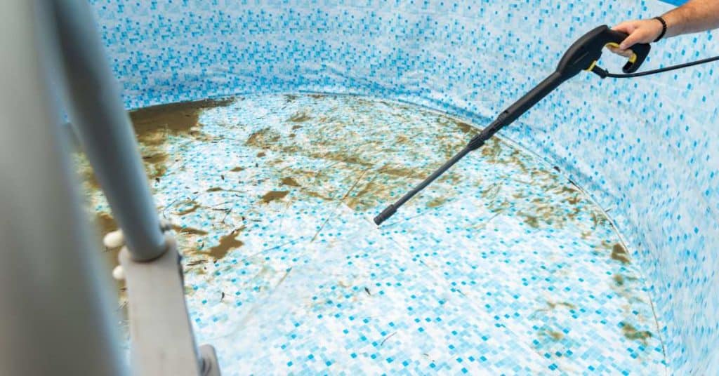 Un homme lave l'intérieur de sa piscine hors sol avec un Kärcher.