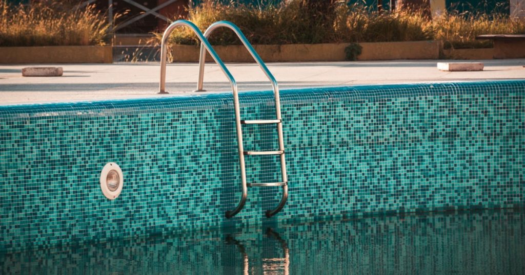 Piscine partiellement vidée. L'eau semble verte.