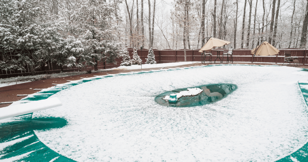 piscine en hiver recouverte d'une bâche avec de la neige dessus