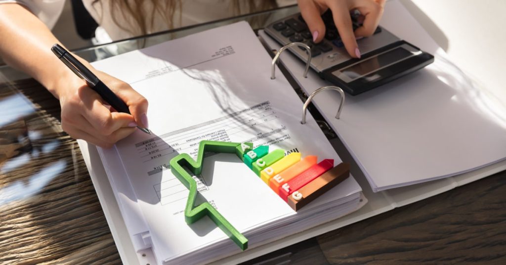 Une femme observe des documents en faisant des calculs à l'aide d'une calculatrice.