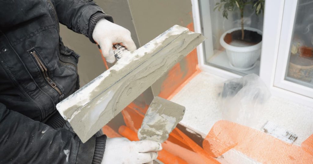 Quelqu'un en train de poser du béton sur un mur 