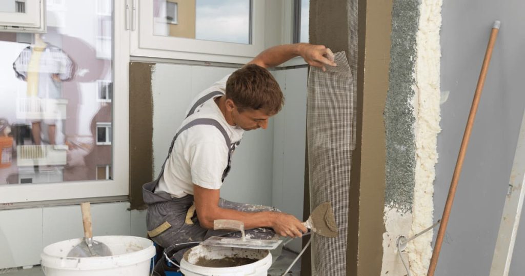 homme refait l'isolation d'un mur intérieur