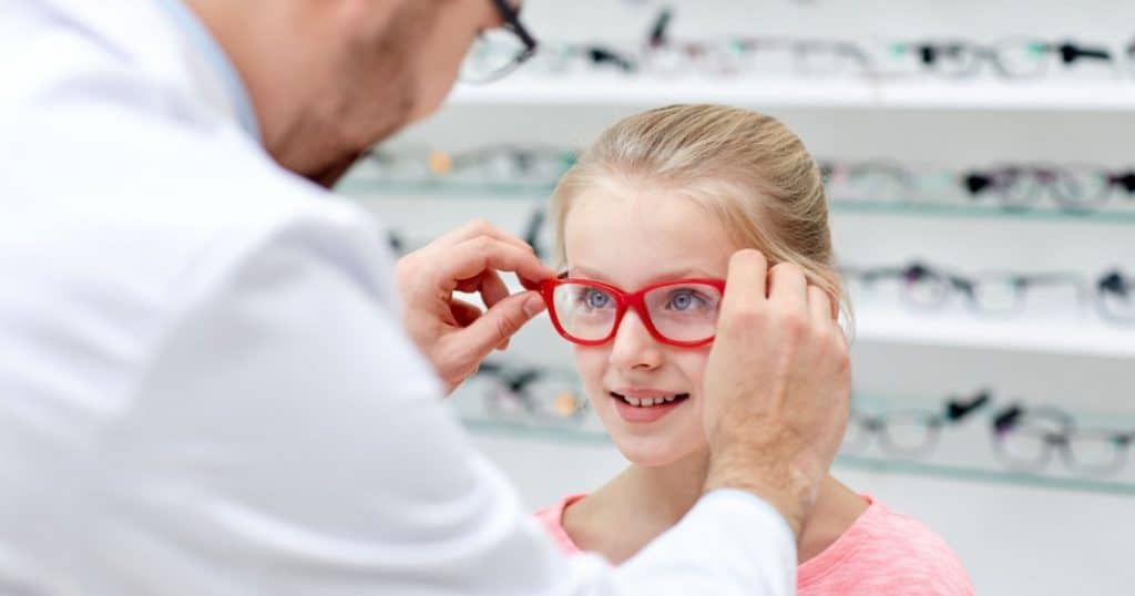 Un opticien met en place les nouvelles lunettes d'une jeune fille. 