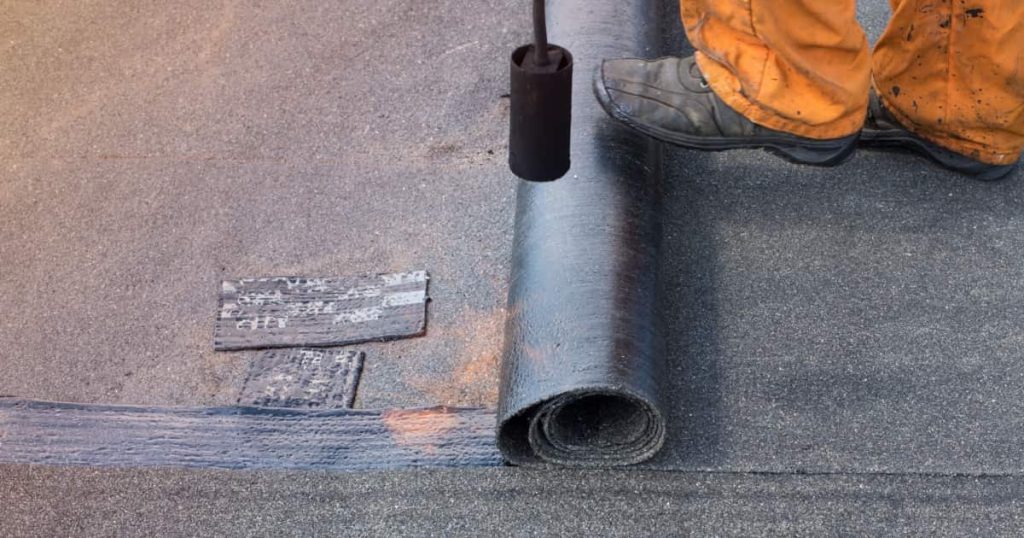 couvreur fixant une couche de bitume  