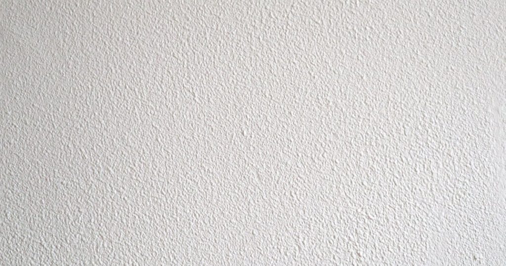 Zoom sur une façade blanche réalisée en crépi gratté. 
