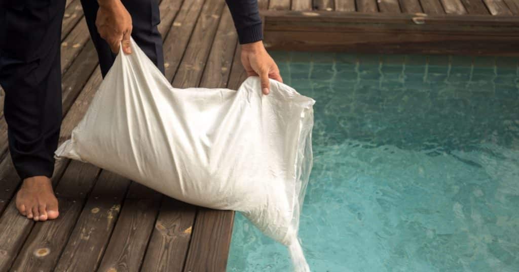 Personne qui déverse un sac de sel dans sa piscine.