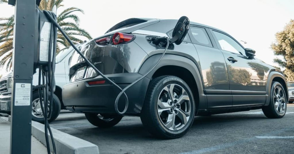 voiture électrique grise de type SUV qui se recharge sur une place de parking 