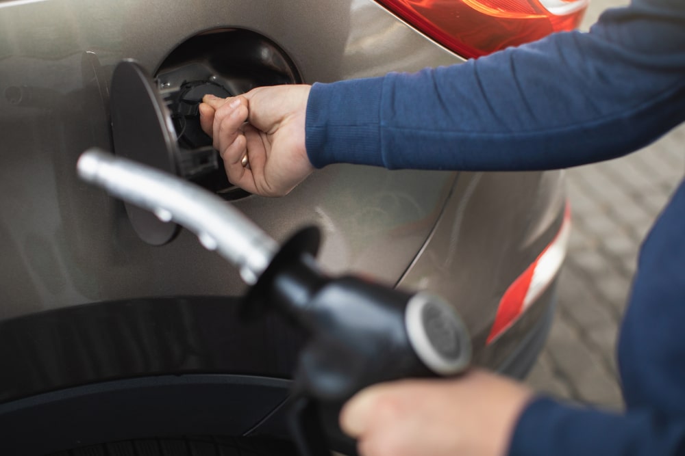 Personne qui ouvre le réservoir de sa voiture pour faire le plein en carburant