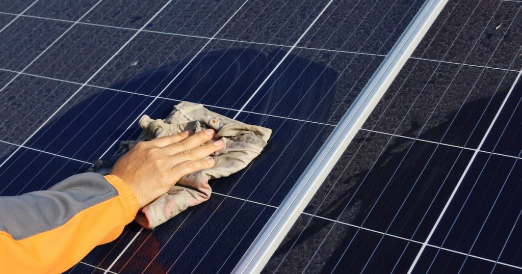 Un homme qui frotte avec un tissu le panneau solaire.