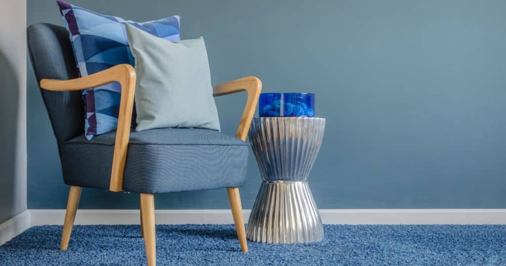 sol de salon en moquette, tapis de couleur bleu s'accordant parfaitement avec un fauteuil bleu