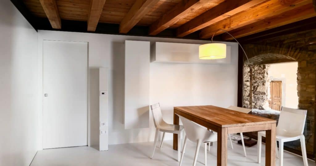 sol en resine blanche d'une salle à manger avec une table en bois et des chaises blanches dans une maison en pierre