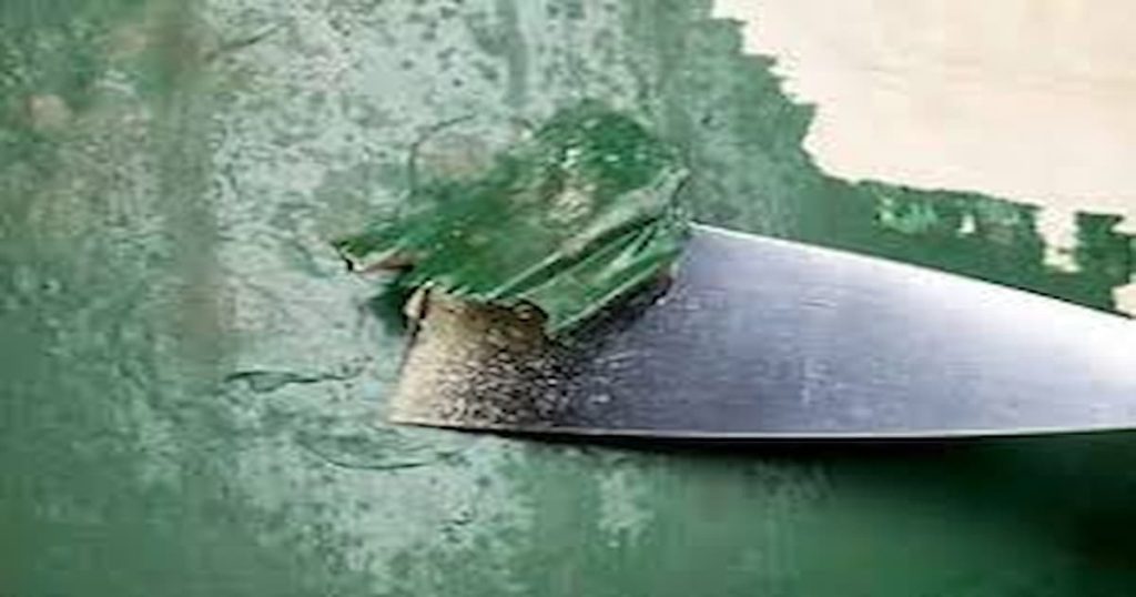 Spatule qui racle une couche de peinture verte après un décapage