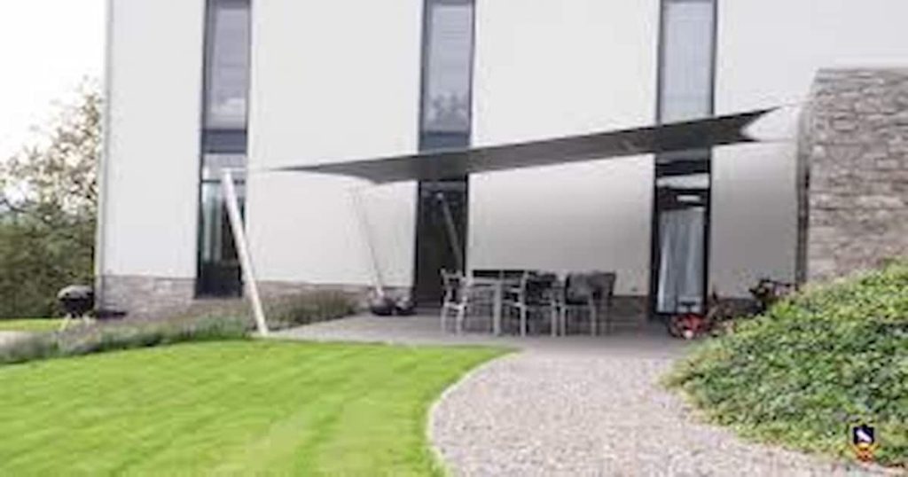 Terrasse avec table et chaises couverte par une toile tendue à côté d'un bâtiment
