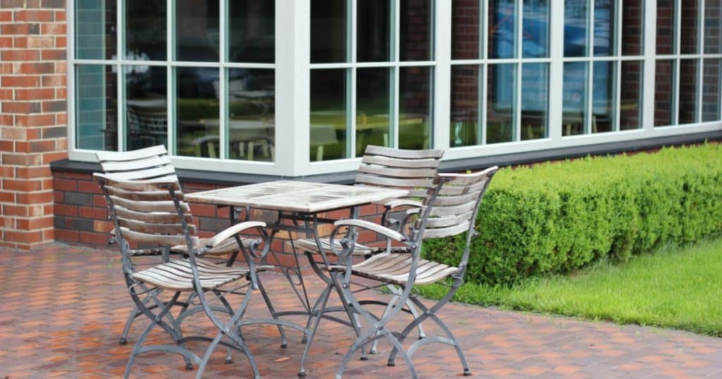 terrasse en klinkers dalles de béton en briques naturelles avec une table et 4 chaises en bois et fer forgé