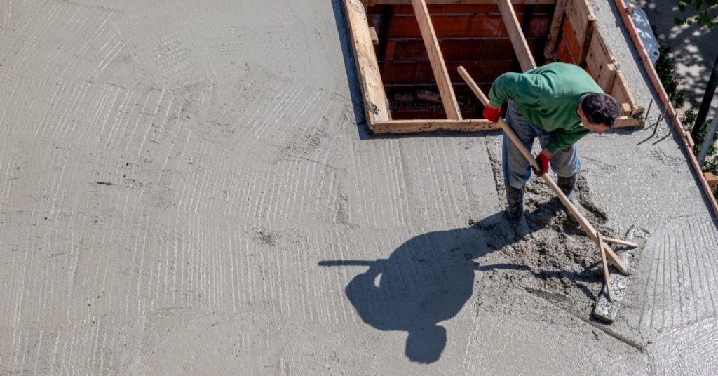 pose de béton sur un toit plat par un ouvrier 