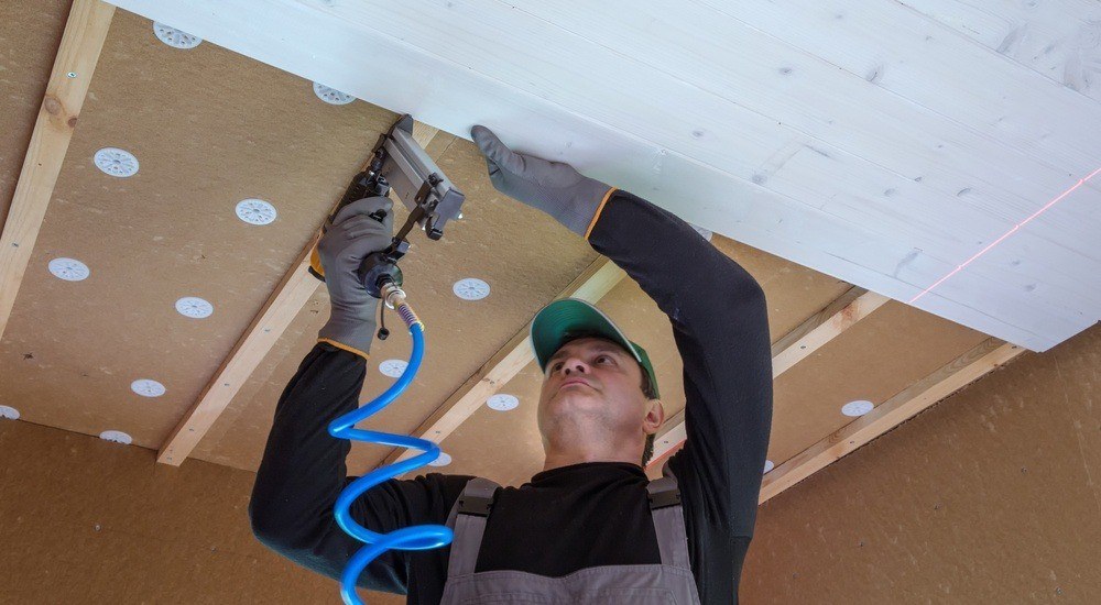 Homme plaçant des plaques d'isolant au plafond