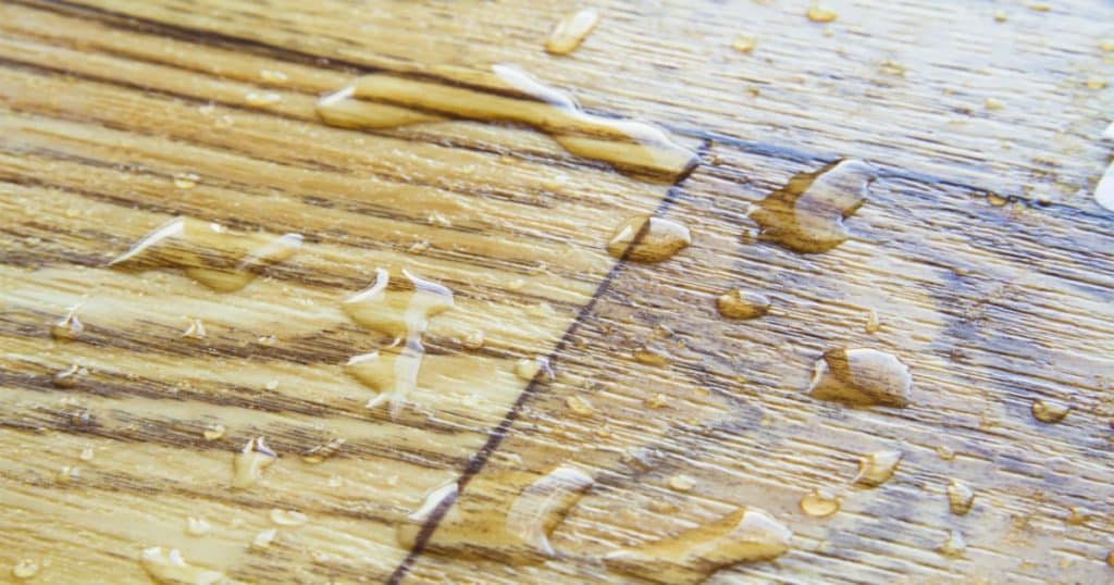 Des traces d'humidité sous forme de gouttelettes sur un parquet en bois. 