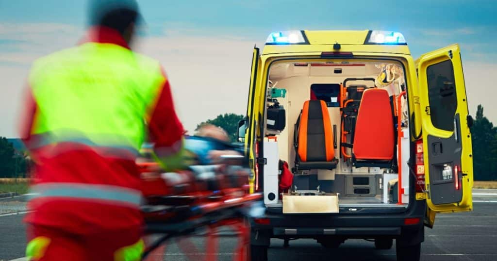 Patient transporté sur une civière dans une ambulance par un ambulancier