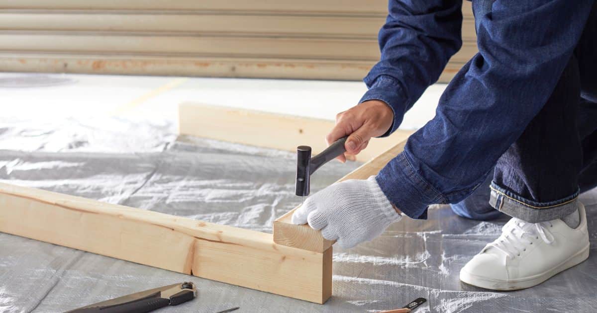 Un homme en train de viser du bois pour monter un escalier