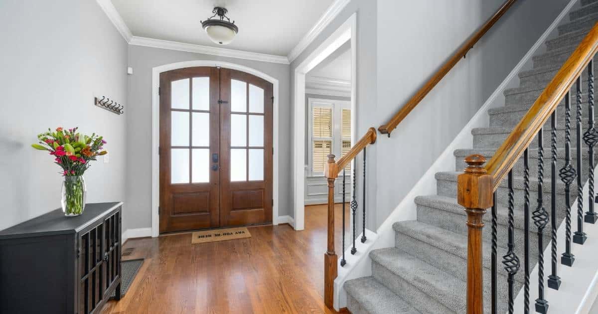 Escalier droit recouvert de moquette avec rampe en bois et en fer forgé