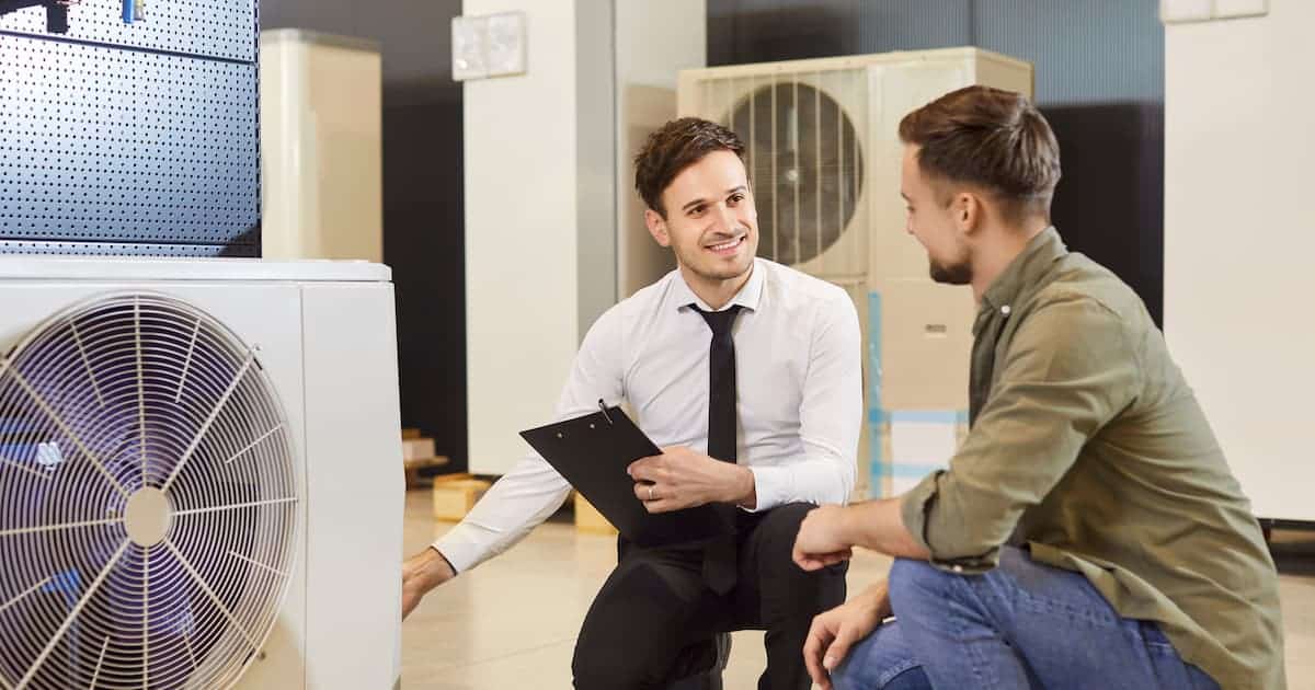 Un spécialiste en climatisation donne des conseils financiers à un client qui est sur le point d'acheter un climatiseur.