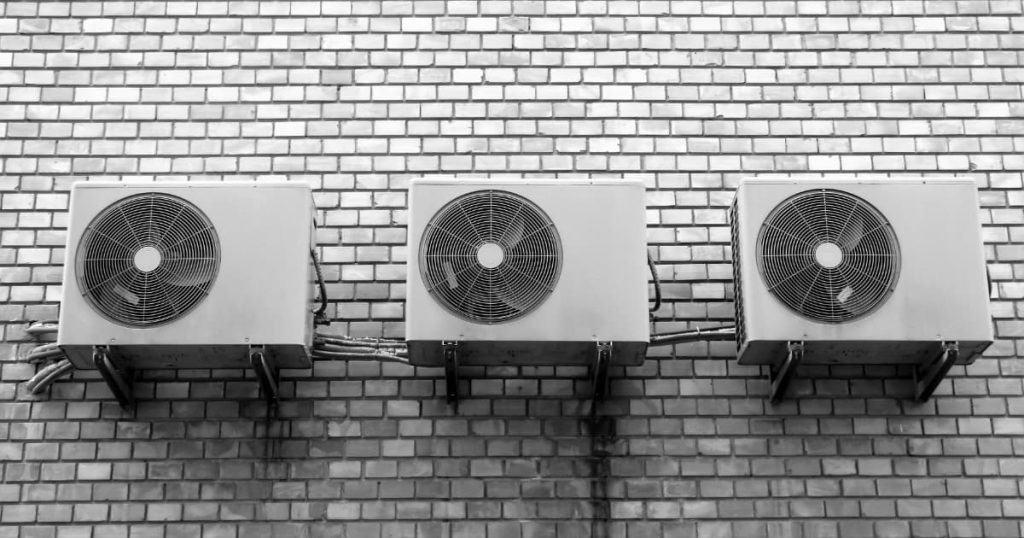 Trois systèmes de ventilation collés sur un mur en brique gris