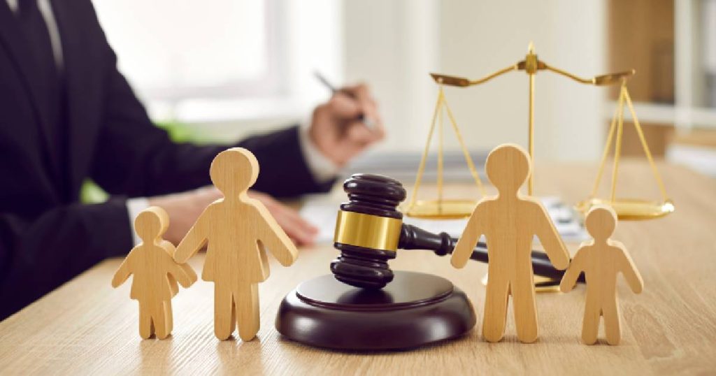 Vier houten poppetjes, twee aan elke zijde van een voorzittersrechter, als symbool voor de rechtsbijstandsverzekering - een optionele aanvulling op wat de familiale verzekering dekt.