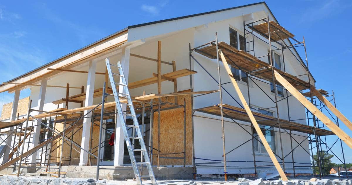 Een gesloopte woning wordt heropgebouwd tot een nieuwbouwhuis. Er staan rondom het huis stijgers en planken