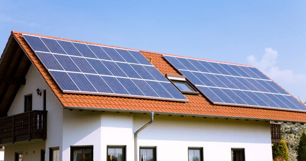 Een oranje pannendak met blauwe zonnepanelen.