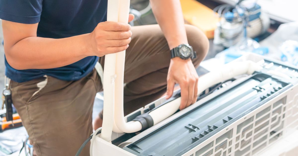 Airco installateur herstelt de koelvloeistofleidingen van een vaste airco binnenunit.