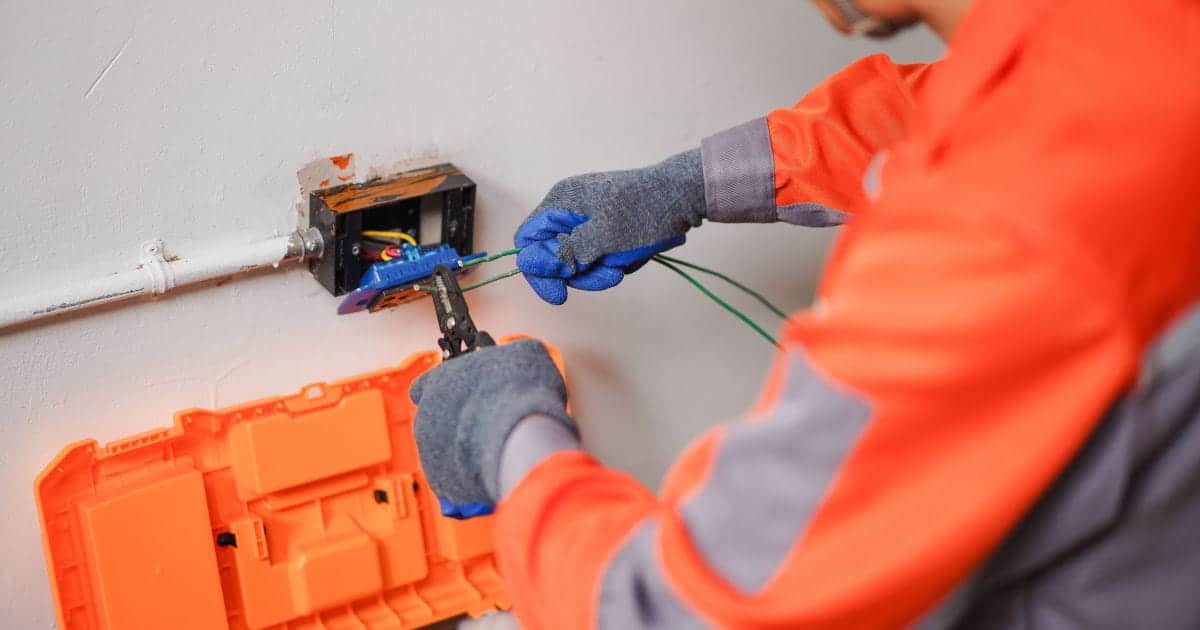 Erkeende elektricien brengt de bekabeling van een stopcontact in orde met de juiste materialen en veiligheidsmaatregelen