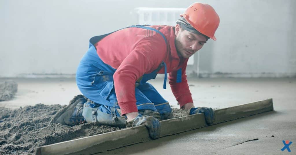 Een chapper in werkkledij en veiligheidshelm egaliseert een verse chapevloer met een reilat.