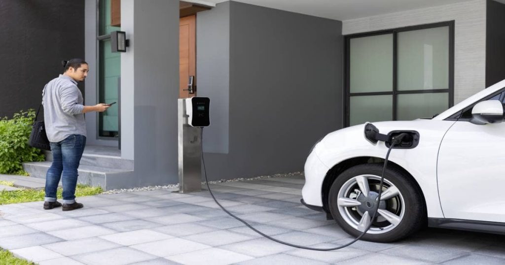 Compacte stijlvolle laadpaal verbonden met auto bij een huis