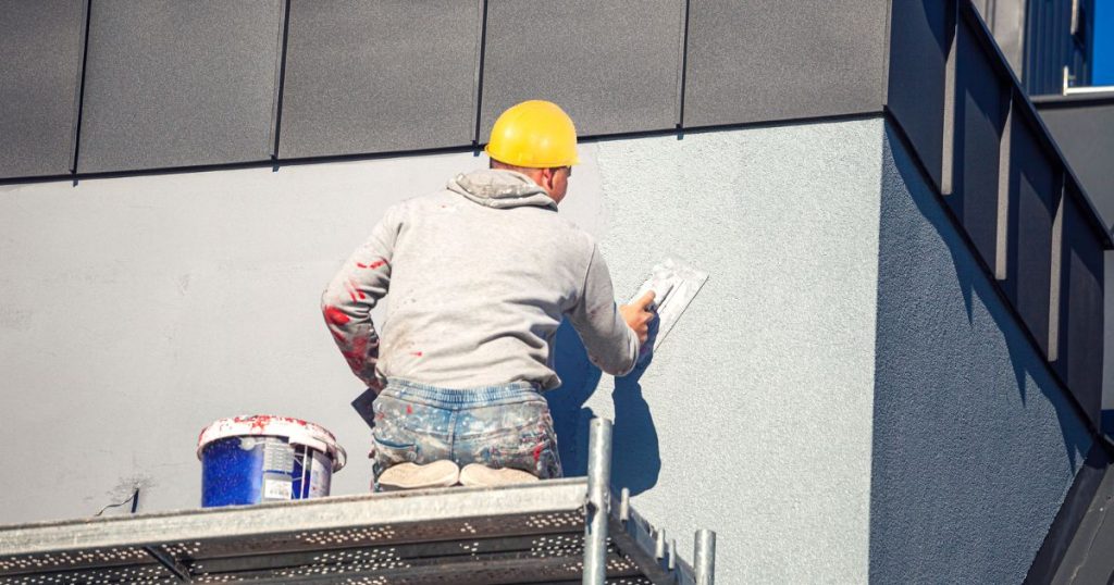 Een professionele gevelwerker brengt kalei aan op de buitenmuur van een woning. De foto toont hoe ervaren vakmensen kaleien uitvoeren om nadelen te beperken.