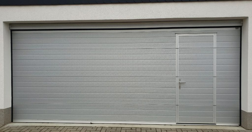 Grijze garagepoort met loopdeur