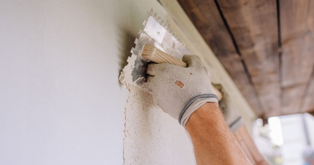 Een gevelspecialist brengt kalei aan op een buitenmuur. Deze afbeelding illustreert het proces en toont enkele kaleien nadelen zoals de technische precisie die nodig is.