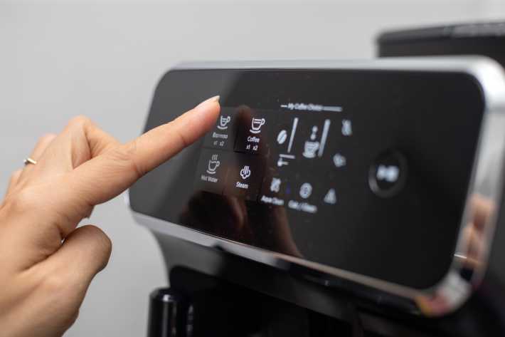 Een dame gebruikt het touchscreen van een koffieautomaat om een kopje koffie te verkrijgen.