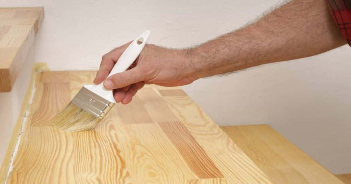 Een vakspecialist zorgt voor de afwerking van een eikenhouten trap: een laagje vernis beschermt het hout en zet de natuurlijke nerven in de kijker.