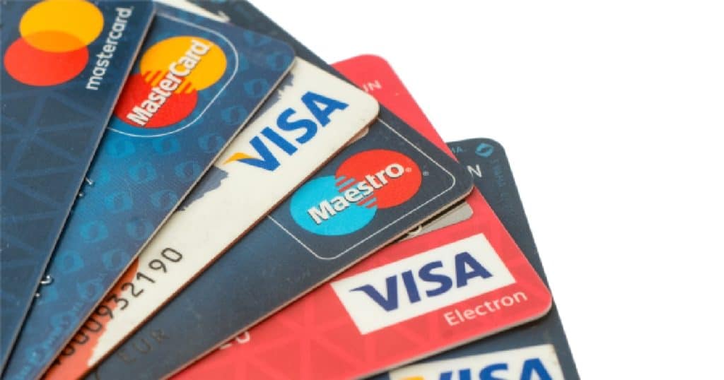 Verschillende betaalkaarten van Maestro, Mastercard en VISA tegen een witte achtergrond.