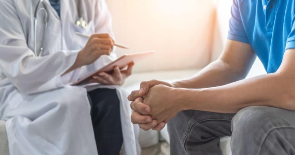 Een patiënt die een consultatie heeft bij een psychiater. De psychiater draagt een witte stoffen jas en houdt een notitietablet met styluspen vast.