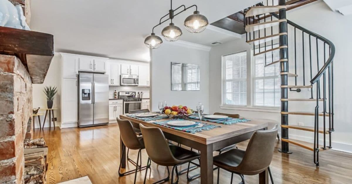 Een zwarte spiltrap met houten treden in een grote keuken met lichtgrijze muren.