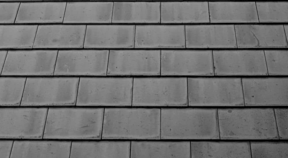 Detailbeeld van een dak met grijs-zwarte tegelpannen.