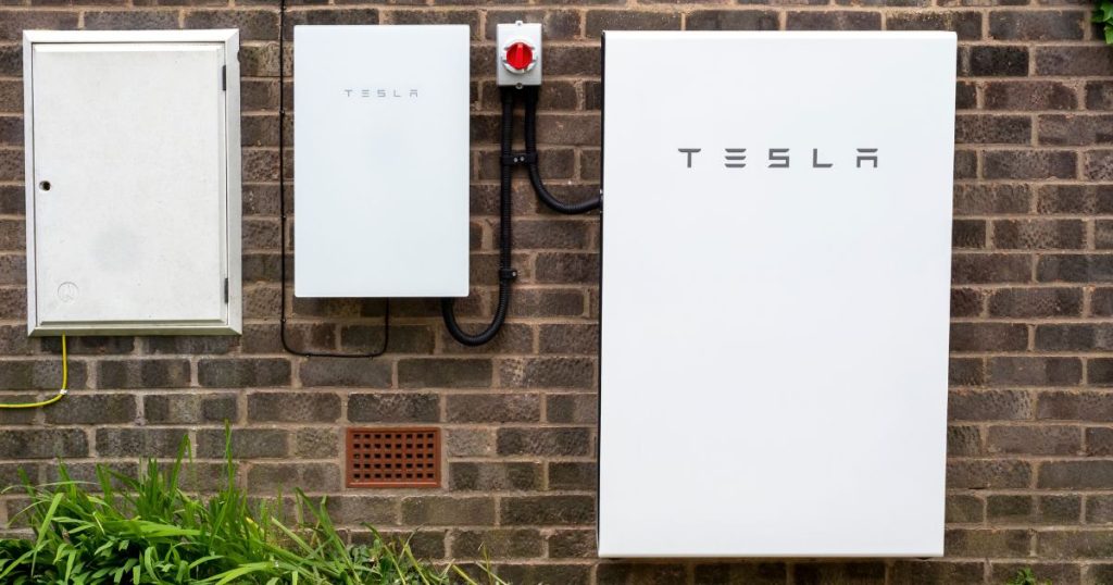 Twee thuisbatterijen van Tesla hangen buiten aan een donkere bakstenen muur.