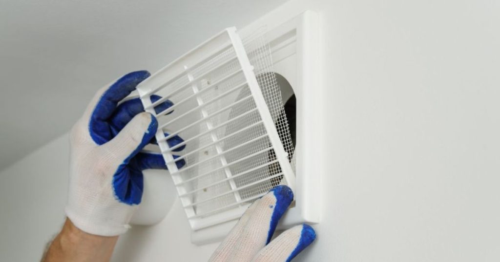 Persoon houdt ventilatierooster vast  voor plaatsing in kruipruimte