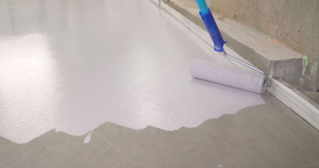 Roller die een witte vloercoating aanbrengt op een betonnen garagevloer